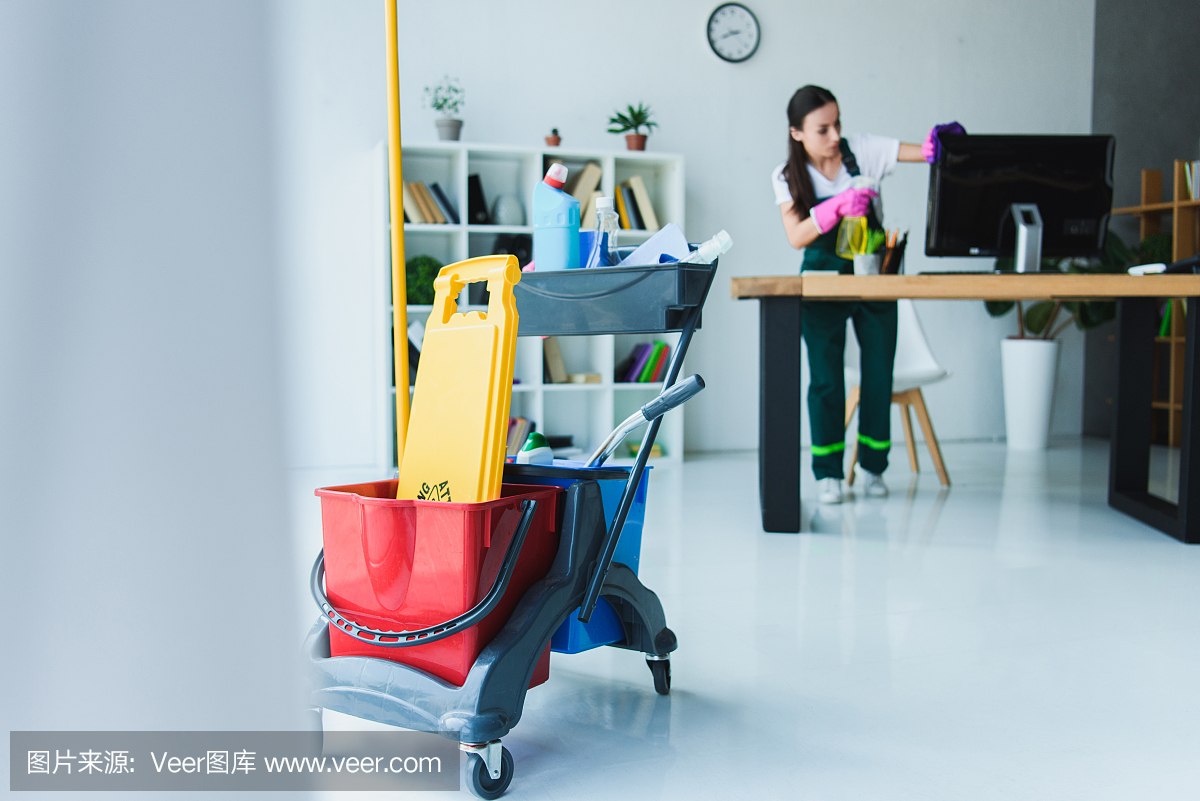 年轻女清洁工用各种清洁设备清洁办公室